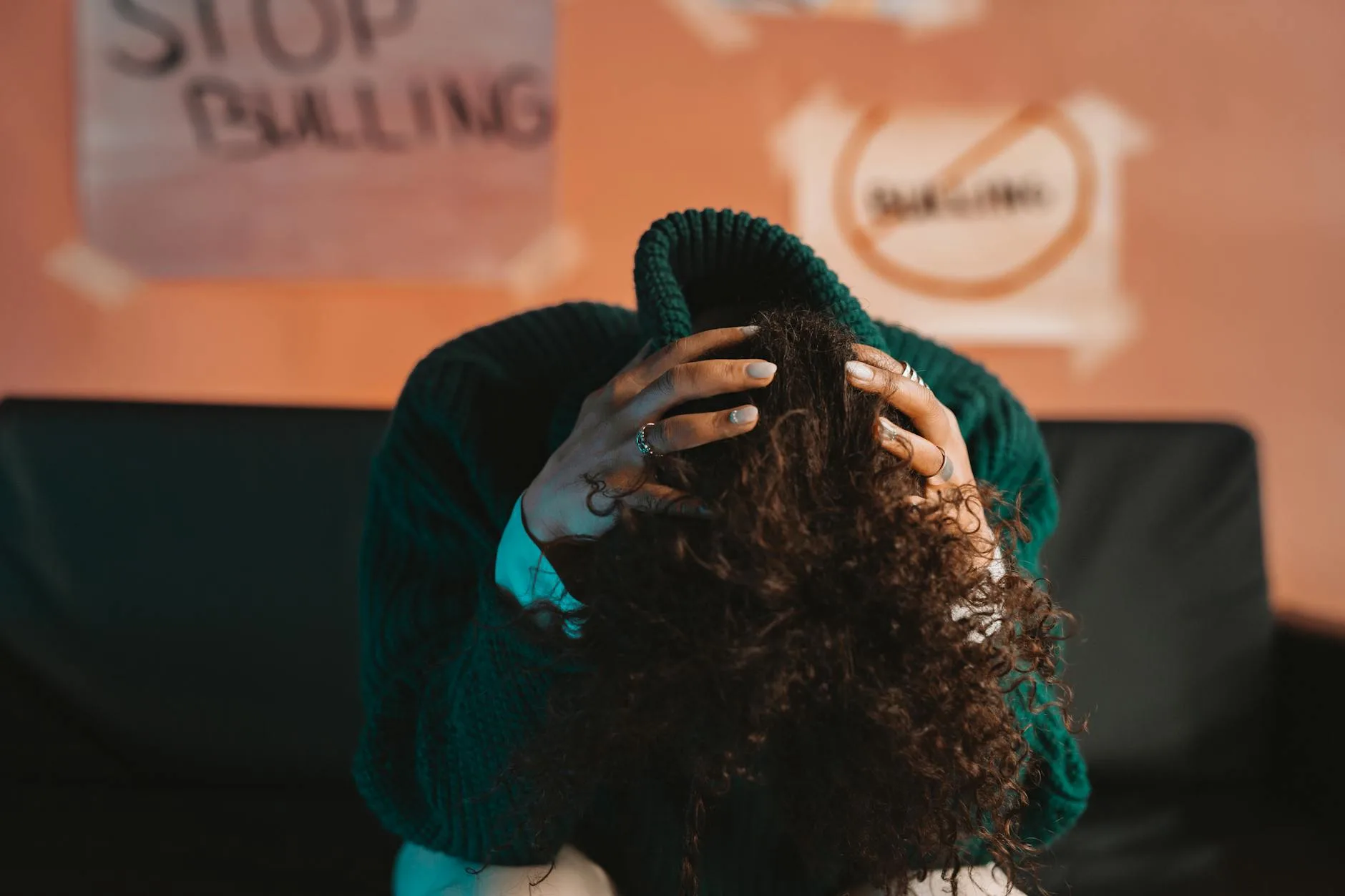 Person bent over with their head on their knees and hands on their head.
