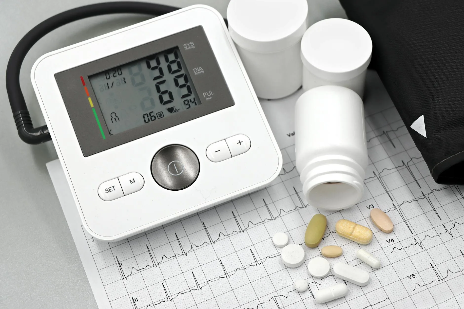 Health tools: a blood pressure monitor, a spilled bottle of pills, and a printout of an EKG.