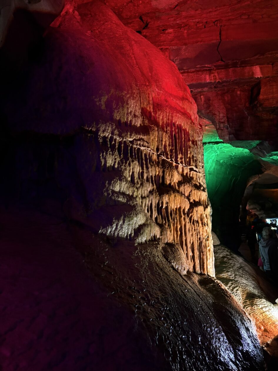 A pipe-organ like formation in a cave, lit from above by red light